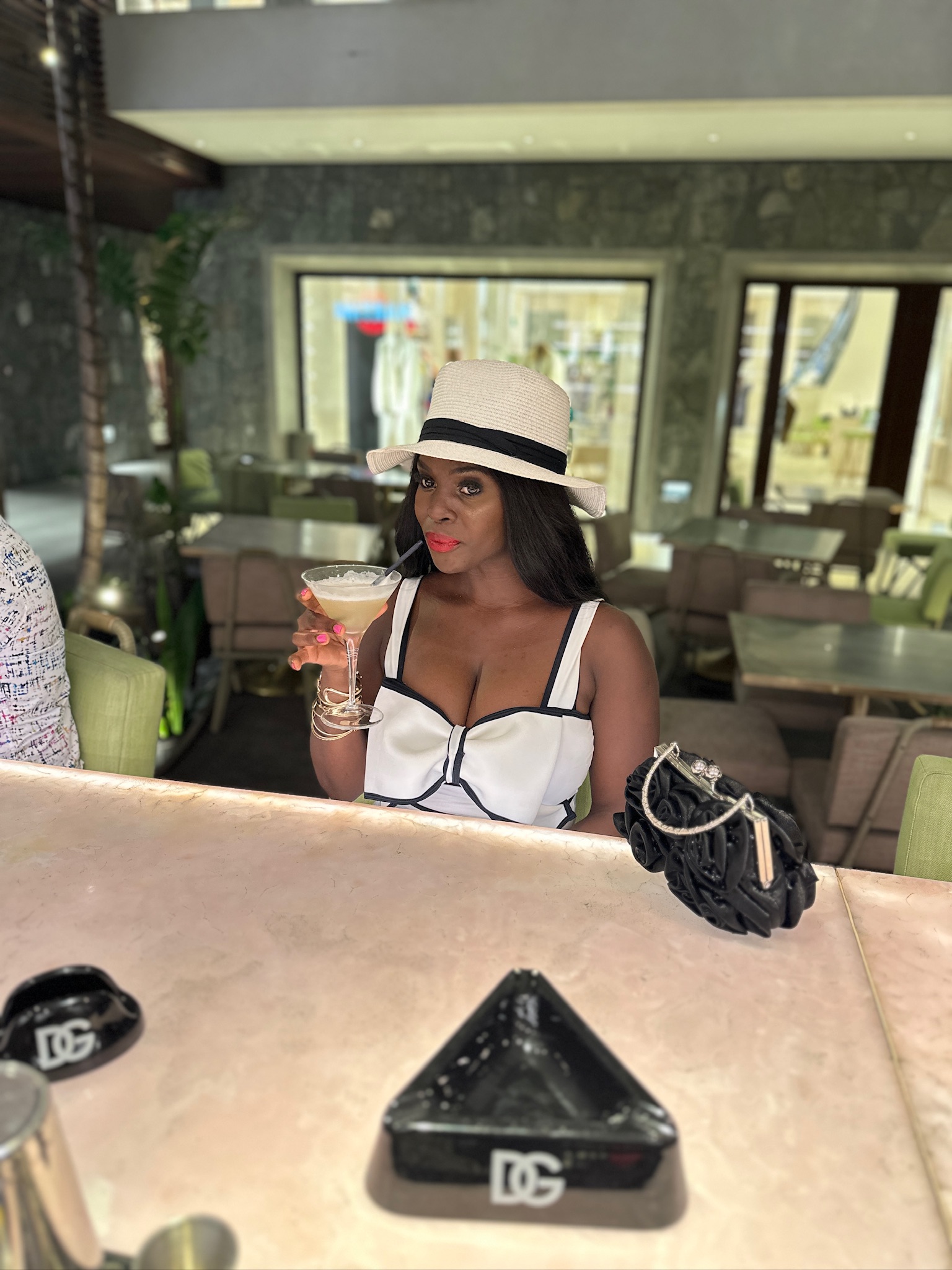 Neola Husbands in St. Barths — Black woman traveler in white sun hat with espresso martini at Nikki Beach, Caribbean luxury travel